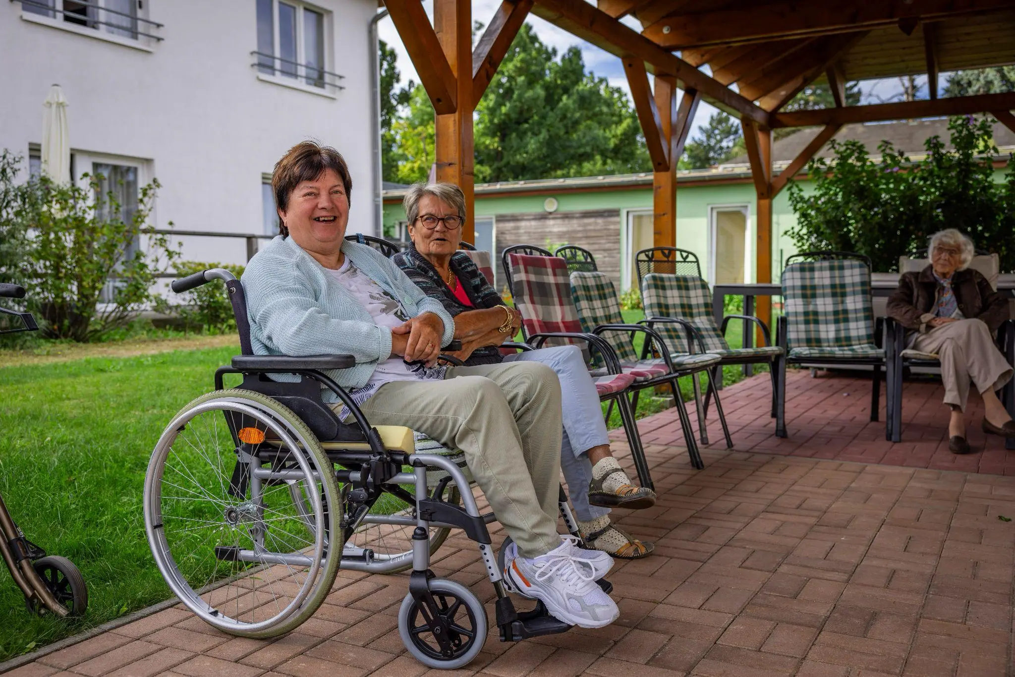 Bewohnerin der Senioren-WG des Pflege- und Betreuungsdienstes Müller sitzt auf einem gepolsterten Gartenstuhl im gemeinsamen Außenbereich.
