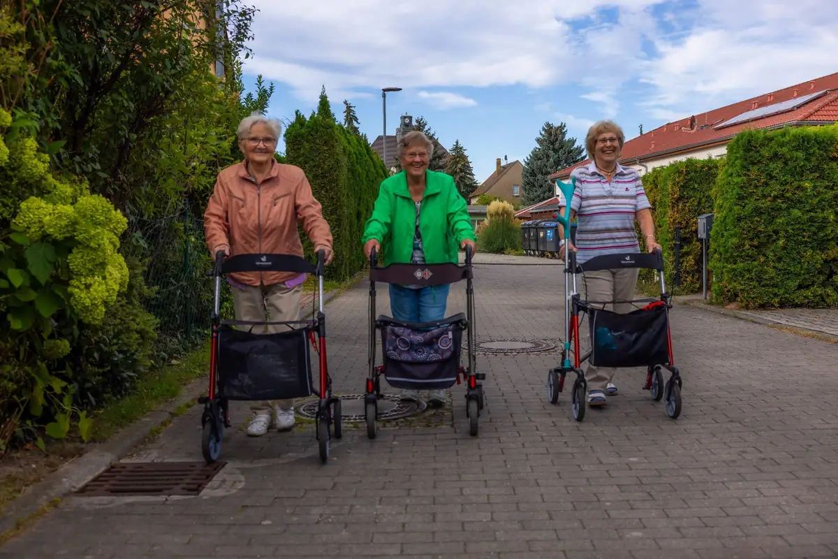 Alltagsbegleitung in der ambulanten Betreuung: Drei Seniorinnen gehen mit Rollator gemeinsam spazieren.